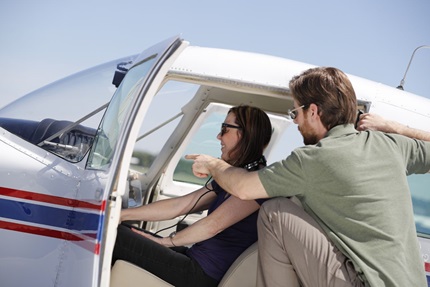 Man standing next to plane instructing woman
